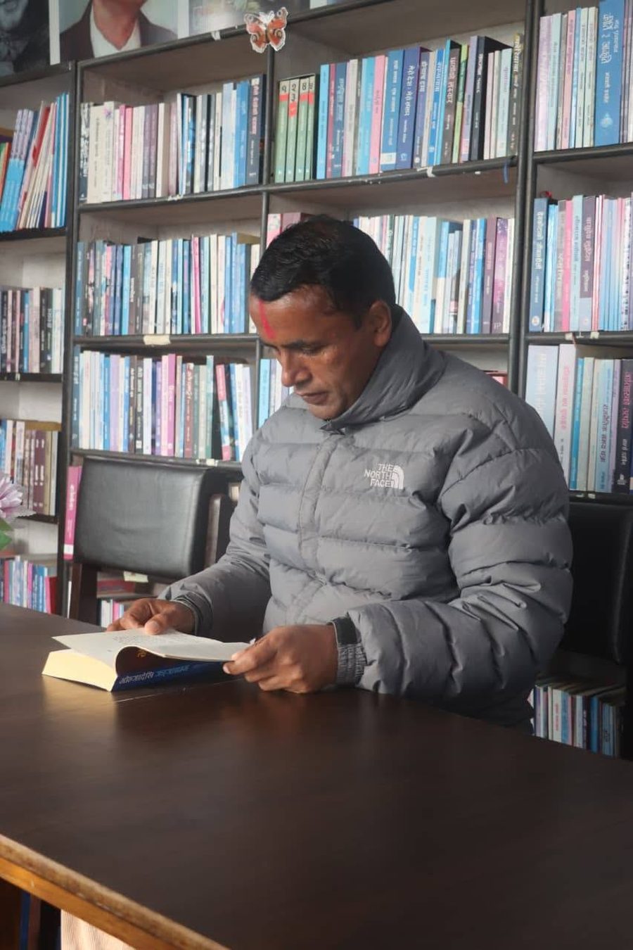 A visitor reading a Nepali-language book at a table in KMRDL