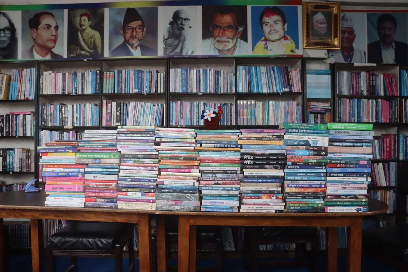 Bookshelves and stacked books at the KMRDL reading hall, with portraits of literary and historical figures on the wall above